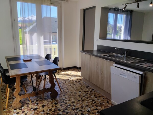 A modern kitchen with a dining area, a dishwasher, and a view of the outdoors.
