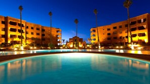 A pool area with a central building and multiple palm trees. - Vancaces Palmeraie Apartment (Marrakech)