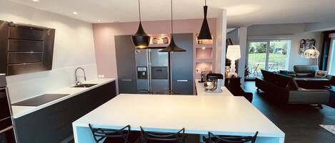 Una cocina moderna con una isla central, taburetes de bar e iluminación colgante.
