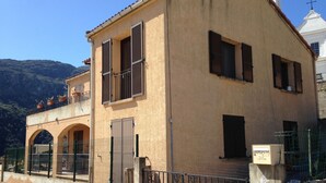 Un edificio a due piani con un balcone, finestre ad arco e un ingresso chiuso da cancello.