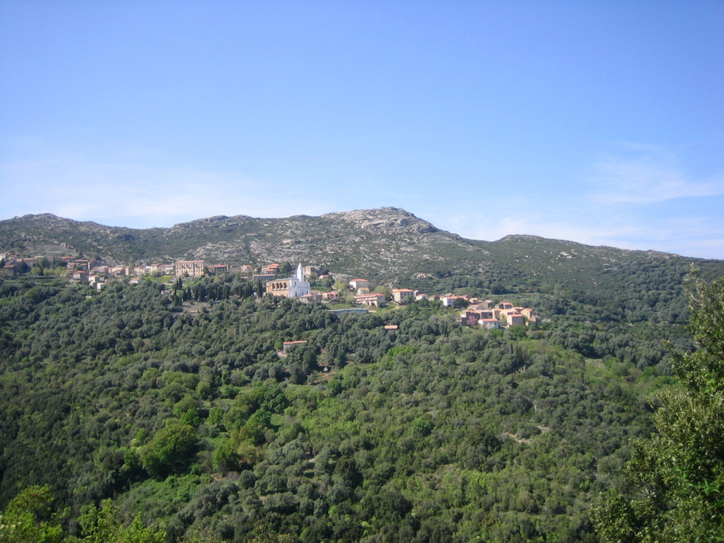 A mountainous landscape with a village and a prominent white church.