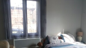 Una camera da letto con un letto, un divano, un tavolino con una pianta, una lampada e una finestra con tende.