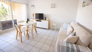 A modern living room with a dining area, a sofa, a TV, and a balcony with a view. - F2 250 m from the beach of Chay Royan (Royan)