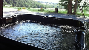 A hot tub with a view of a forested area and a road in the background. - Maison De La Residence Celeste (Ogenne-Camptort)