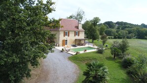 A two-story house with a swimming pool, surrounded by lush greenery and a gravel driveway. - Maison De La Residence Celeste (Ogenne-Camptort)
