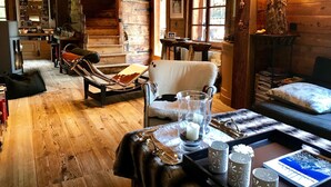Interior acolhedor de uma cabana de madeira, com área de jantar, sofá e lareira.