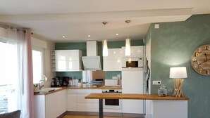 A modern kitchen with white cabinets, a wooden countertop, and a dining area with a table and chairs.