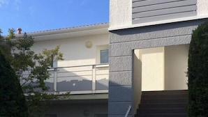 A modern building with a grey exterior, a staircase leading to a balcony, and a clear sky.