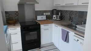Eine kleine Küche mit einem schwarzen Herd, einem Toaster und einer Kaffeemaschine.