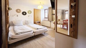 A compact room with two beds, a wooden wardrobe, a small table, and a mirror. - Rempart - Large studio in the centre of the village (Eguisheim)
