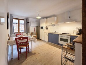 A compact kitchen with a dining area, a microwave, an oven, and a coffee maker.