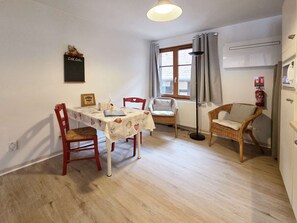 A dining area with a table, chairs, a floor lamp, and a fire extinguisher. - Rempart - Large studio in the centre of the village (Eguisheim)