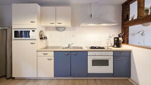 A compact kitchen with a microwave, sink, stove, and cabinets. - Rempart - Large studio in the centre of the village (Eguisheim)