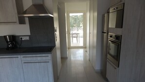Una cucina moderna con mobili bianchi, una cappa aspirante in acciaio inossidabile e un forno integrato.