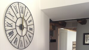 Ein Flur mit einer großen Wanduhr, Holzboden und einer Tür zu einem anderen Raum.