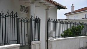 A white building with a black wrought iron gate and a white door. - The Orange Terrace (Antibes)