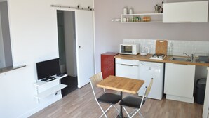 A compact kitchen with a microwave, stove, and sink. There is a small dining table with chairs. - The Orange Terrace (Antibes)