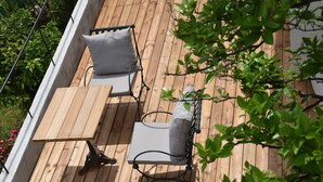 A wooden deck with two chairs and a table, surrounded by greenery. - The Orange Terrace (Antibes)