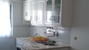 Una cocina con armarios blancos, un lavamanos y un colgador de luz.
