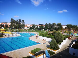 Une grande piscine extérieure dotée de plusieurs couloirs de nage, entourée d’un espace paysager avec des marches menant à la piscine.