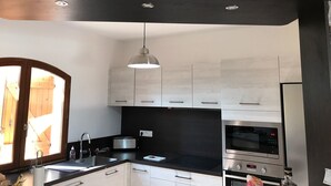 Une cuisine moderne avec un mur d’accent en pierre, des appareils électroménagers intégrés et une grande fenêtre.