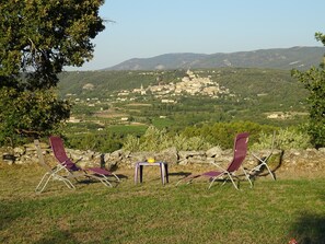 Two lounge chairs facing a scenic view of a village and mountains. - Cante Grillet in LACOSTE (84) in PROVENCE Quiet countryside Chambre FANNY (LACOSTE)