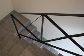 Una escalera con barandilla metálica y escalones grises.