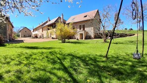 A stone building with a sloped roof, surrounded by a well-maintained lawn and a small tree. - "6 PEOPLE, LES PERRIERES, BURGUNDY SAS MAYMARD ANTULLY 0611375830 (3 vacation rentals = 17 people)" (Antully)