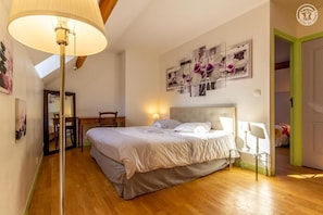 A bedroom with a bed, a desk, and a chair. There are wall-mounted lamps and a ceiling light.