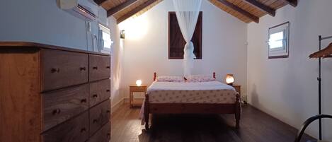 A bedroom with a wooden ceiling, a bed with a canopy, a dresser, bedside lamps, and a window.