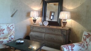 Una habitación con un aparador de madera, dos lámparas, un reloj y sillas con estampado floral.