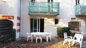 Un bâtiment à deux étages doté d’un balcon, d’une table avec des chaises et d’un portail.