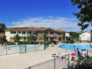 A resort with a large swimming pool, multiple buildings, and a clear blue sky. - Small charming villa Soulac sur mer (Soulac-Sur-Mer)