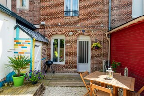 A brick house with a red garage door, a wooden deck, and a table with chairs.