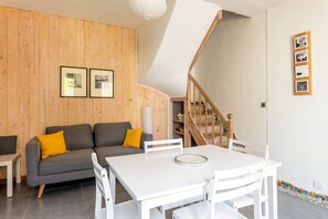 A modern living room with a grey sofa, white table, and wooden panel walls.