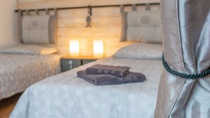 A bedroom with two beds, a wooden headboard, bedside lamps, and a curtain.