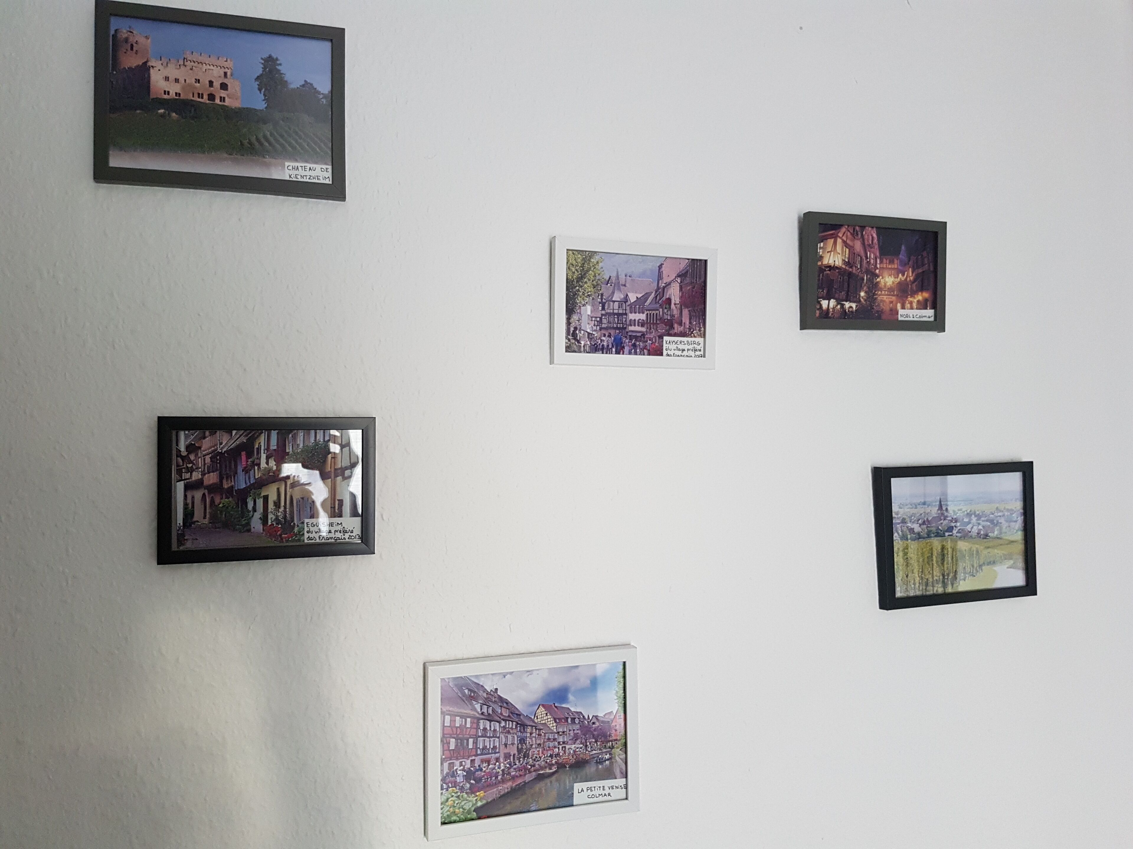 Eine Wand mit sechs gerahmten Bildern von verschiedenen Gebäuden und Landschaften.