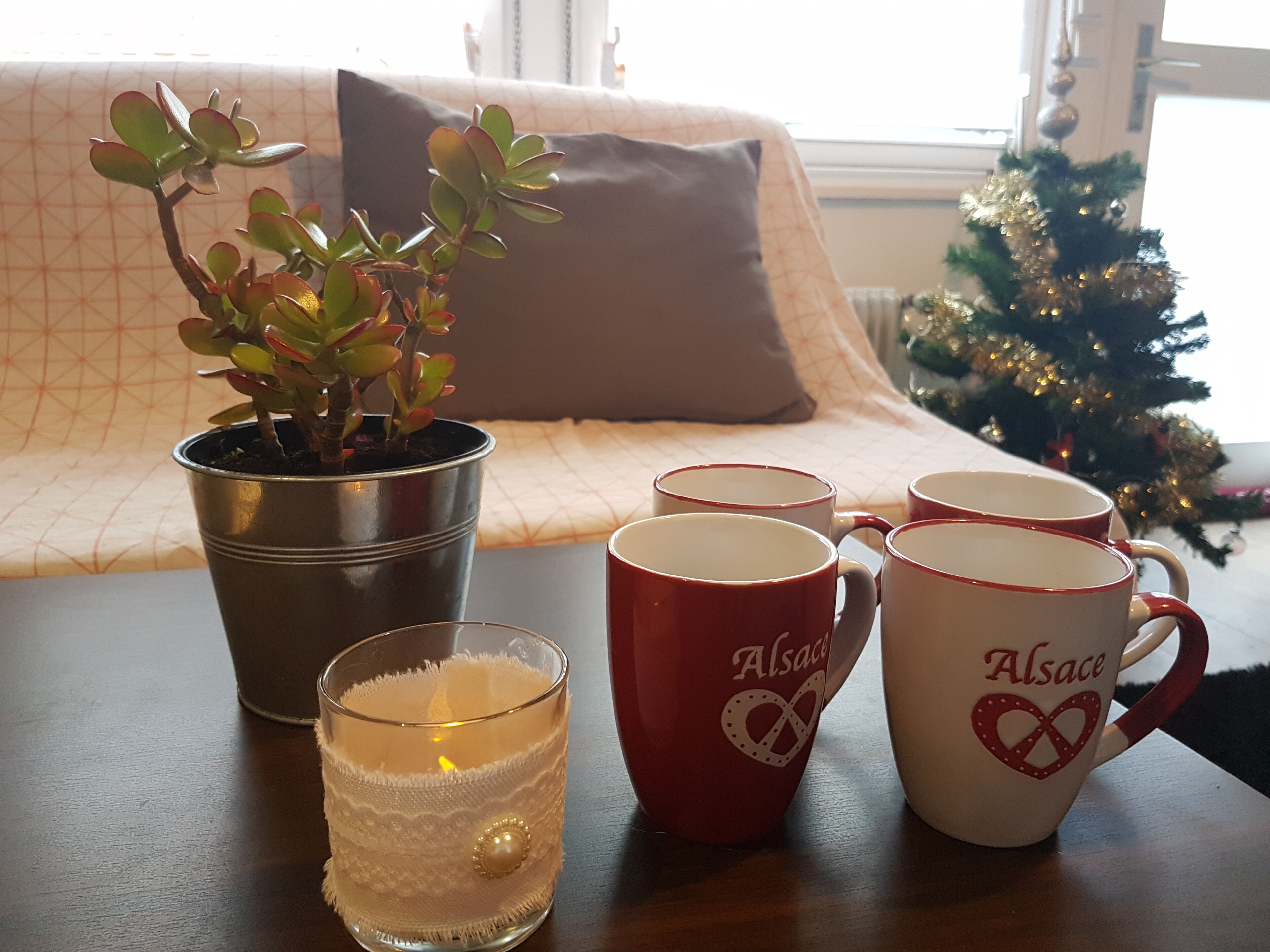 Un ambiente interior acogedor con una planta en maceta, un candelabro de cristal y un juego de tazas sobre una mesa.