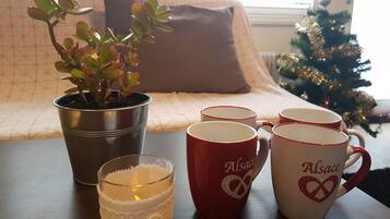Un ambiente interior acogedor con una planta en maceta, un candelabro de cristal y un juego de tazas sobre una mesa.