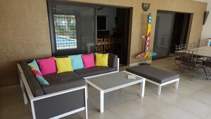 Een moderne woonruimte met een modulaire bank, een witte salontafel en een eettafel met stoelen.