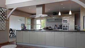 A modern kitchen with a central island, stainless steel appliances, and pendant lighting. - Very beautiful luxury villa (Sainte-Luce)