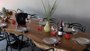 A dining table set with plates, glasses, and a bottle of wine, surrounded by chairs. - Very beautiful luxury villa (Sainte-Luce)