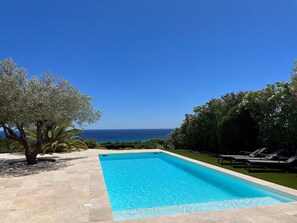A rectangular swimming pool with clear blue water, surrounded by a tiled deck.
