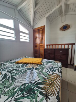 Quarto com cama, guarda-roupa de madeira e janela.
