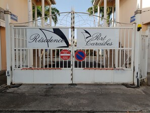 Uma entrada fechada por portão com placas que indicam “Residence” e “Port Caribes”.