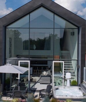 A modern house with large glass windows, a patio with outdoor furniture, and a hot tub. - Maison D'Architecte in one of France's most beautiful villages (Bergheim)