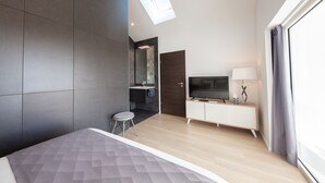 A modern bedroom with a skylight, a TV, and a bedside table. - Maison D'Architecte in one of France's most beautiful villages (Bergheim)
