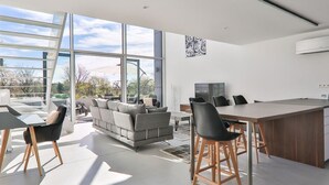 A modern kitchen with a large island, bar stools, and a dining area with a sofa and chairs. - Maison D'Architecte in one of France's most beautiful villages (Bergheim)