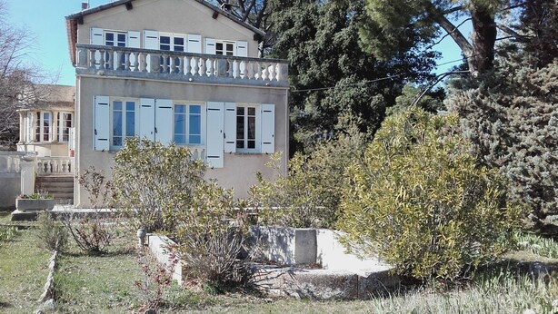 A two-story building with a balcony, surrounded by trees and shrubs. - LARGE COUNTRY HOUSE in the South Luberon (Cabrières d Aigues)