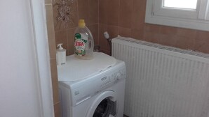 A washing machine with a detergent bottle on top, a radiator, and a window above the machine. - LARGE COUNTRY HOUSE in the South Luberon (Cabrières d Aigues)